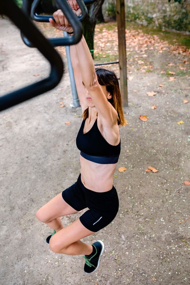 Unrecognizable woman doing monkey exercises on rings