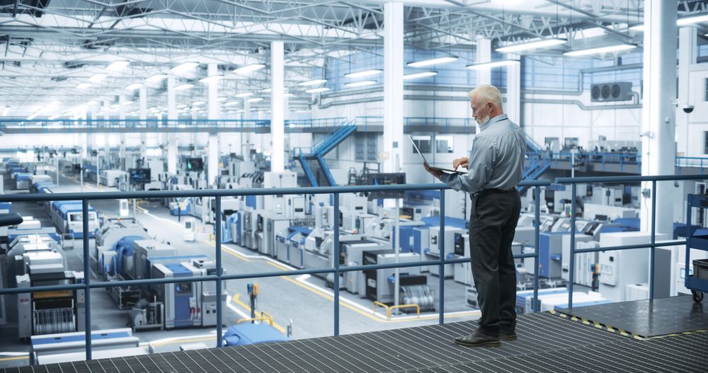 Thoughtful Engineer Monitoring and Analyzing Conditions at a Pristine Modern Electronics Factory with Automated Mobility Robots Working with the Help of Artificial Intelligence Software