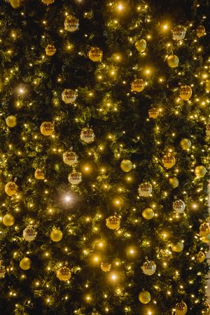 Gold baubles on lit Christmas tree in close-up