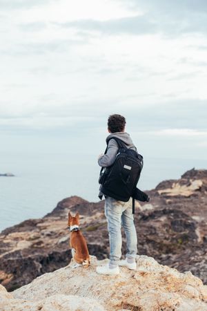 Solo trekker with dog on the coast looking over the sea