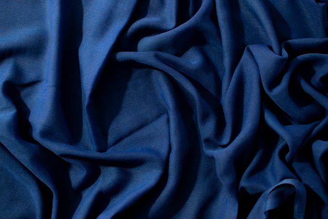 Navy or dark blue fabric wavy spiral crumpled background texture with copy space in the center.