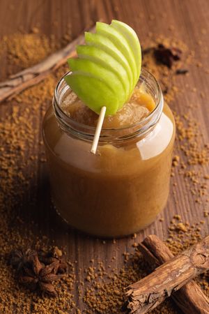 Delicious applesauce in glass jar and cinnamon