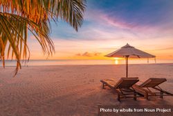 Two relaxing beach chairs with umbrella at the beach at sunset 0LBYe4