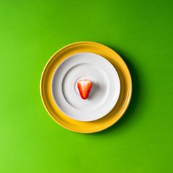 Strawberry half on plate setup on green background