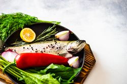 Trout fish ready for cooking with lemon, onion and pepper