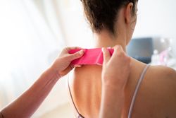 Kinesiology tape on back of neck being applied in modern clinic