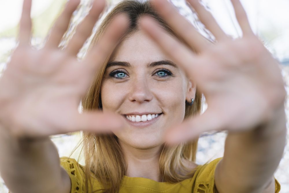 Young smiling woman pulling hands to camera