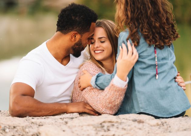 Cheerful multiethnic family cuddling on nature