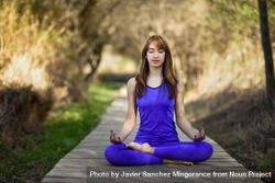 Female wearing purple sport clothes in lotus pose 0PVG74