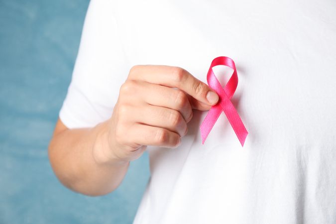 Person in t-shirt hold awareness ribbon against blue background