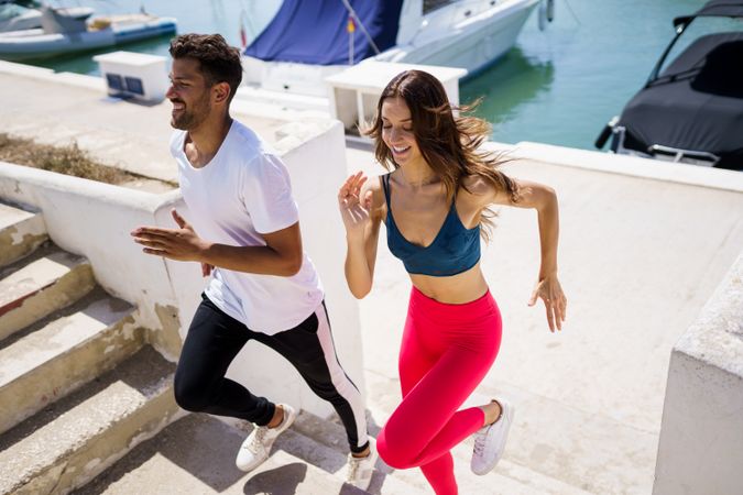 Man and woman working out on stairs near waterfront