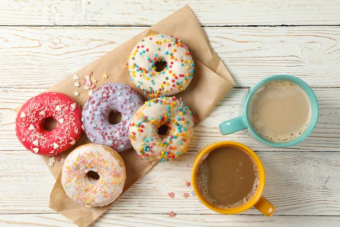Coffee and tasty donuts on wooden background, top view