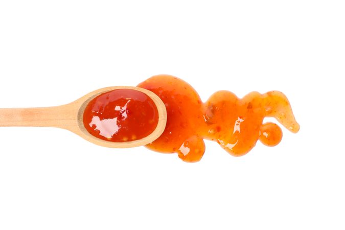 Spoon with hot sauce isolated on blank background