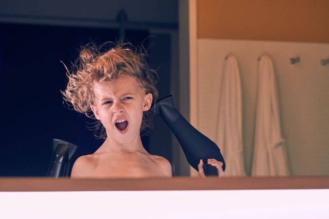 Cute boy blow drying hair