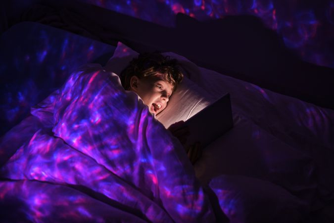 Amazed boy browsing tablet at night time