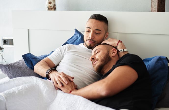 Smiling gay couple hugging on bed