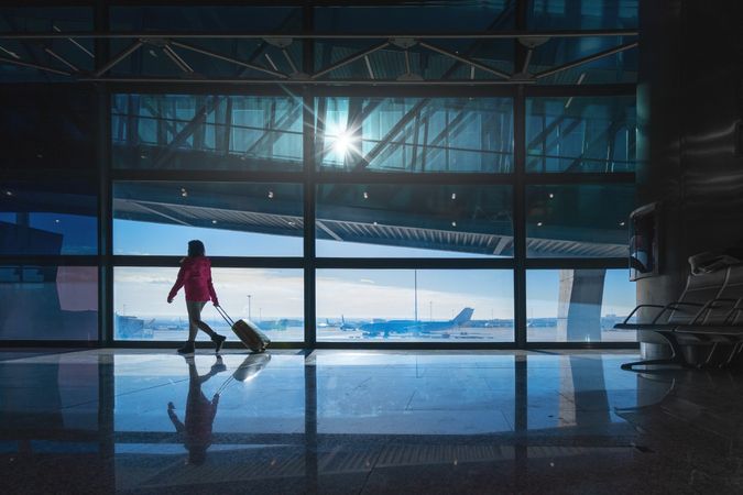 Anonymous female with luggage walking in empty airport