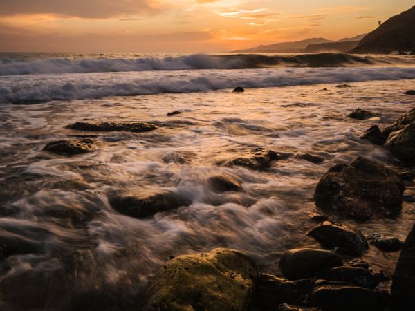 Stony seashore and waves at beautiful sunset