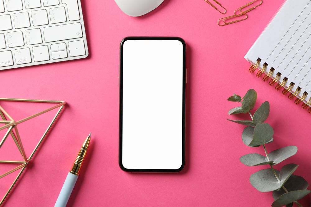 Workplace with phone with empty screen, top view