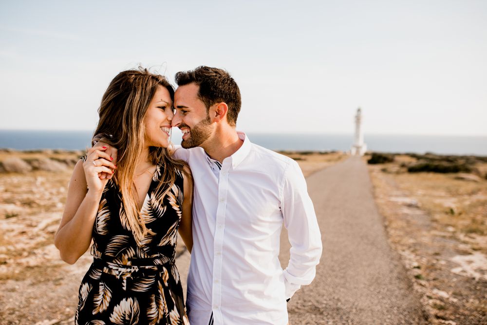Smiling lovers cuddling on path to sea