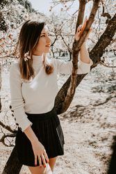 Young happy woman between trees in garden