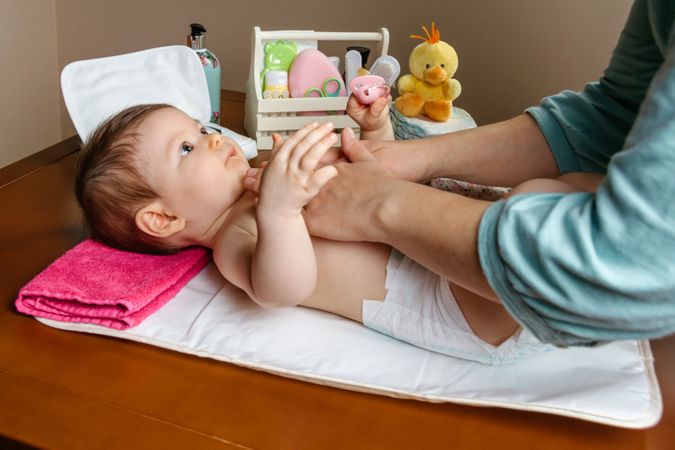 Mother playing with baby during diaper change