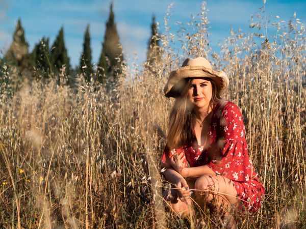Happy dreamy woman sitting among high grass