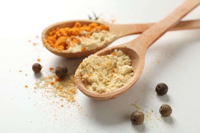 Close up of two wooden spoons full of spice