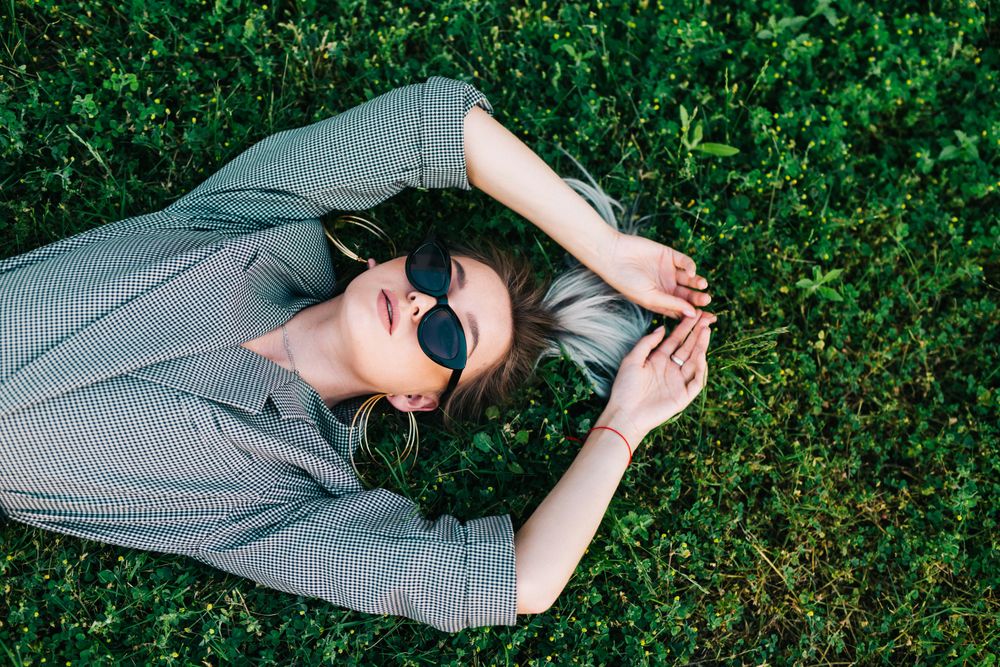 Woman in stylish suit lying in grass