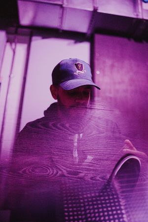 Magenta and purple tinted abstract double exposure of young man in cap and wood floor