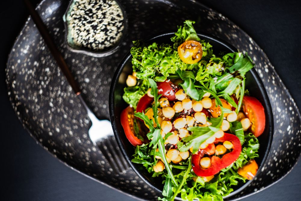 Top view of organic vegetable salad with garbanzo beans and side of sesame seeds