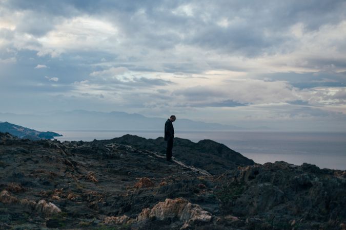 Solitary man watches sunset on horizon of the coast