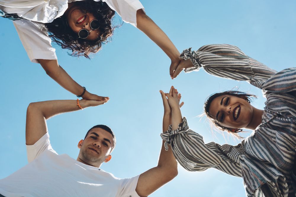 Group of friends embraced and putting their hands together.