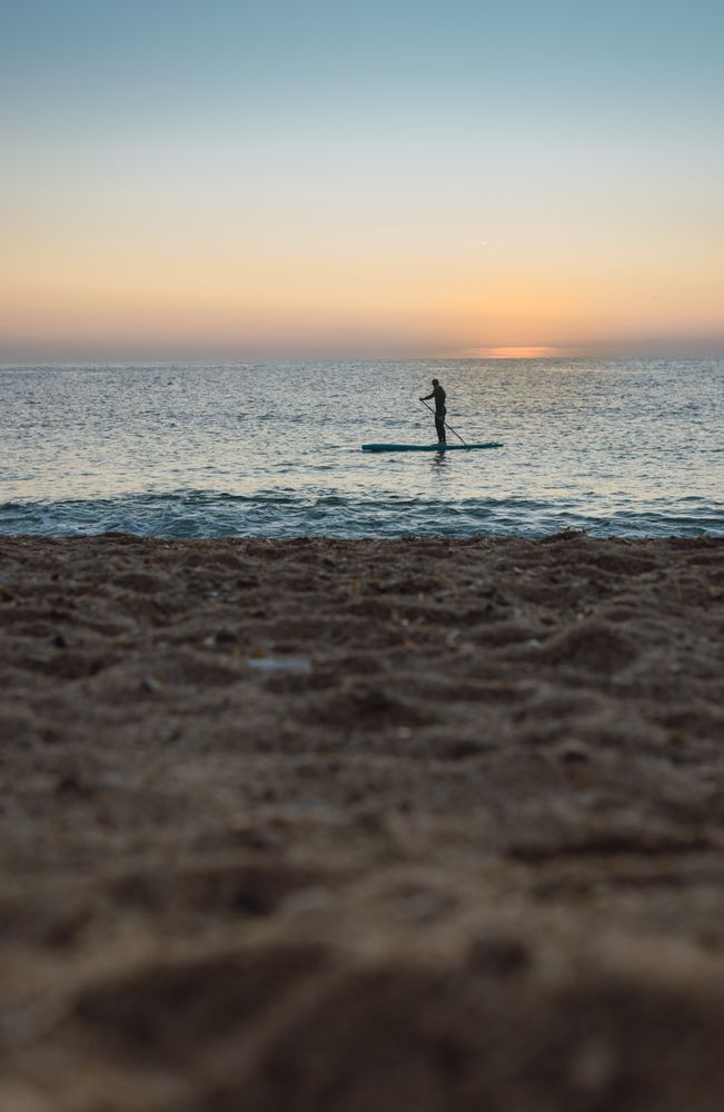 Man practicing paddle surfing with neoprene in a sunrise