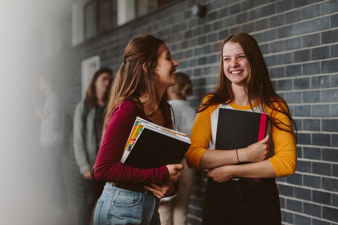 Portrait of smiling girls walking through high school corridor after their class