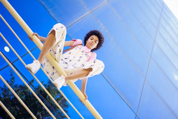 Low angle shot of woman sitting on handrails in front of  reflective building