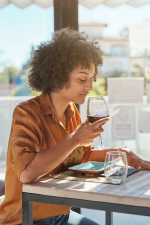 Hispanic woman sitting in restaurant and drinking wine