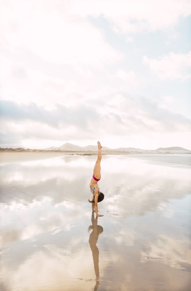 Woman doing handstand near sea