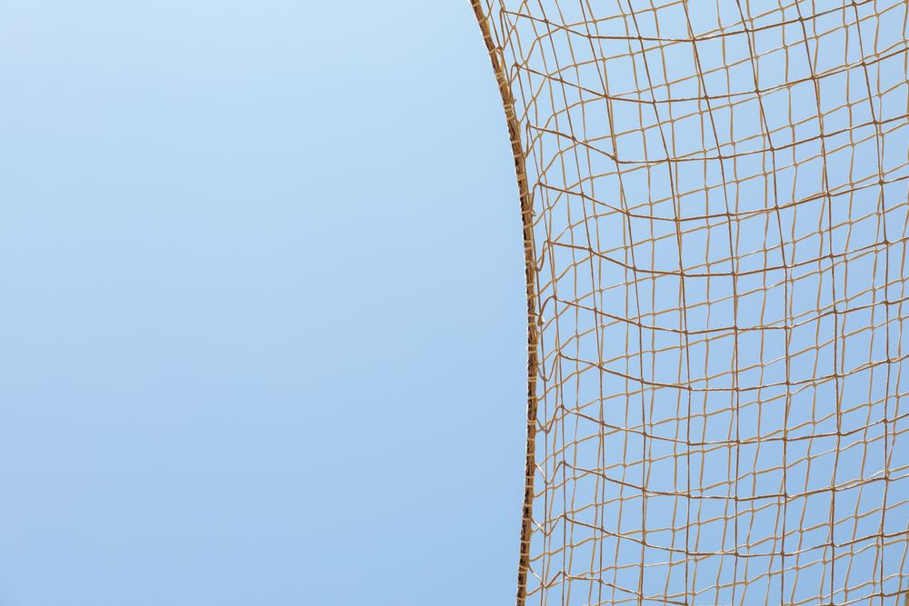 Football net against blue sky background, space for text