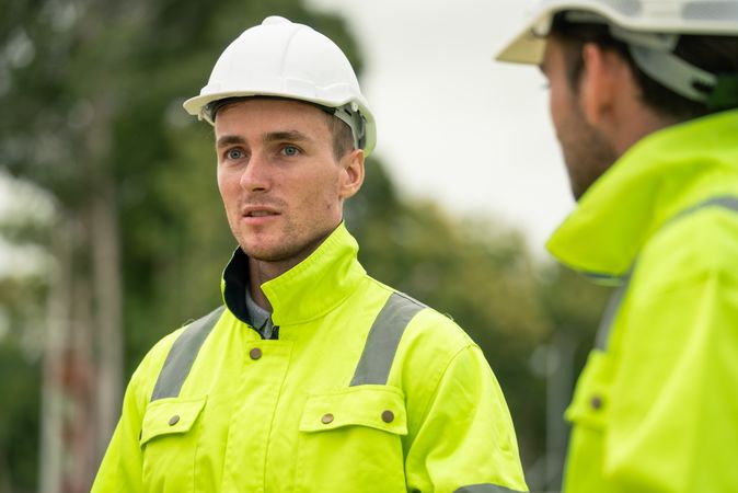Engineer worker in protective uniform talking with colleagues at construction site