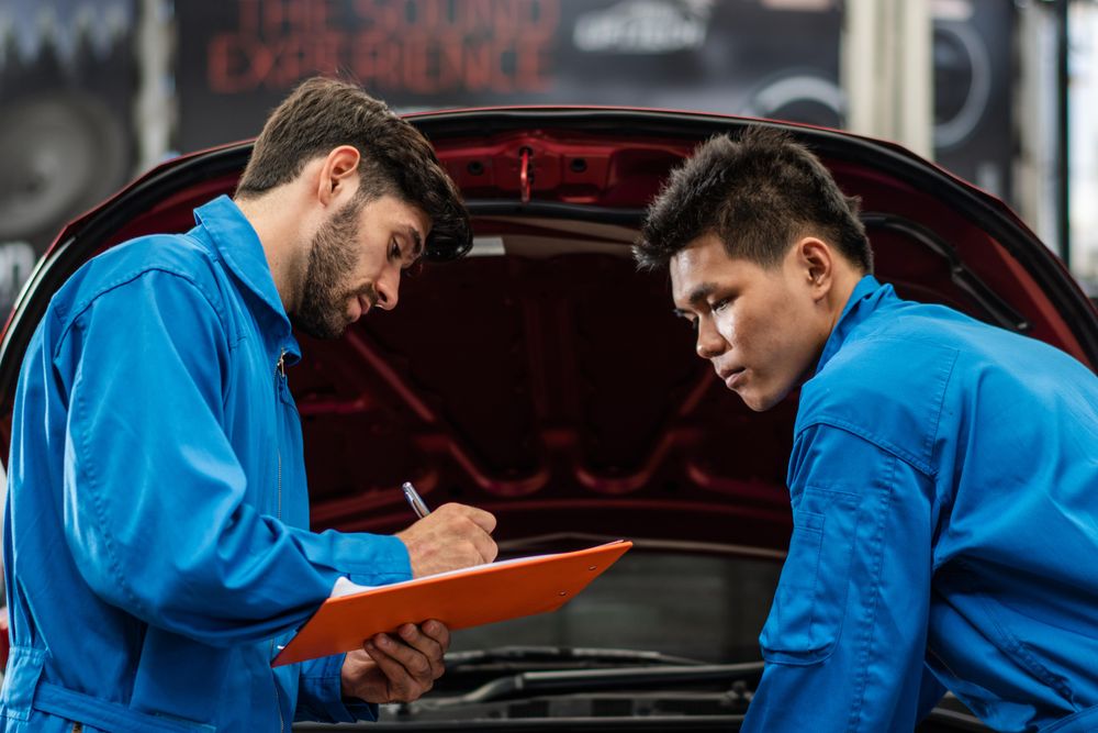Two male auto workers standing with clipboard in front of vehicle