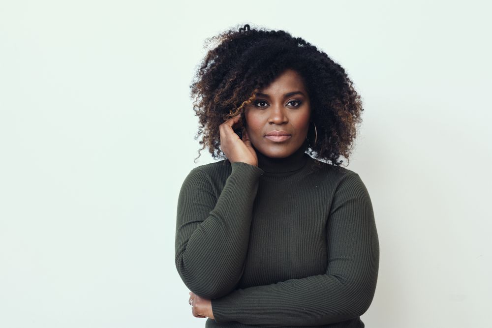 Black woman touching her ear and looking at camera
