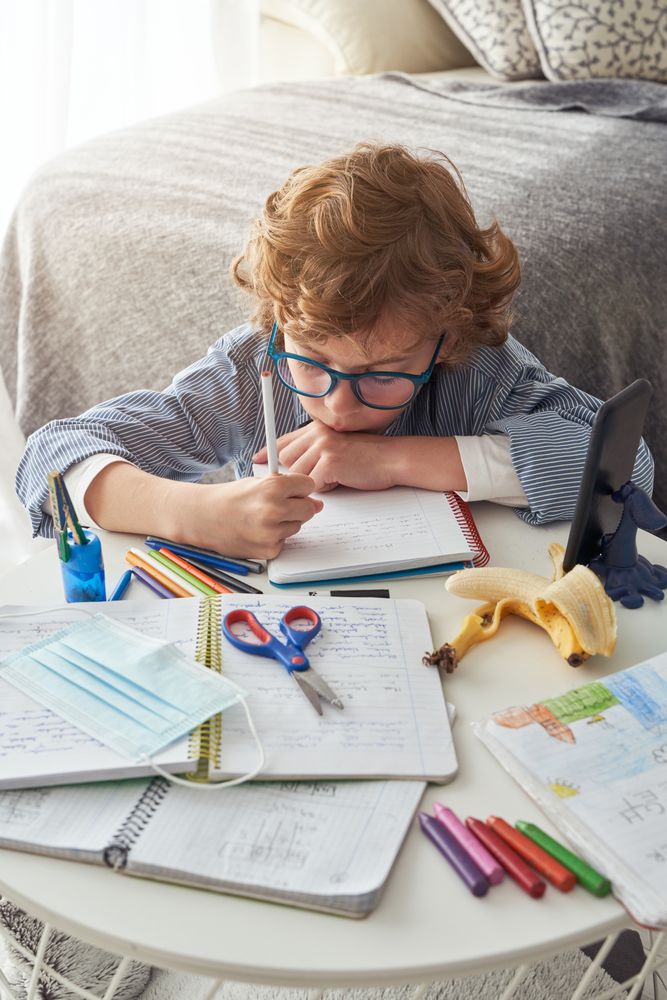 Adorable boy taking notes in notebook at home