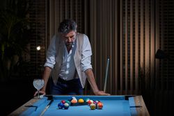 Mature male leaning on pool table and thinking about game