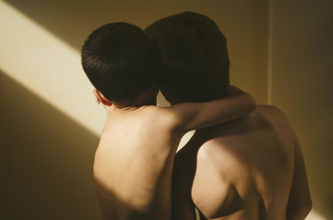Two boys hugging looking at wall