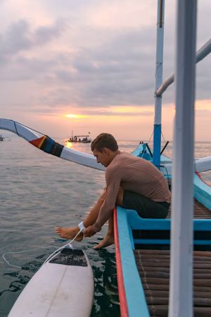 Men diving from boat in waving water at sunset