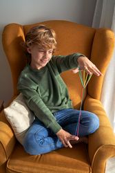 Cheerful boy with long colourful string playing game
