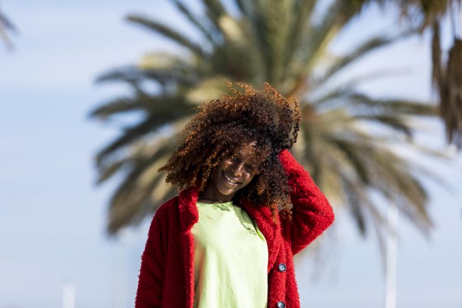 Female with hand to her curly hair smiling on sunny day