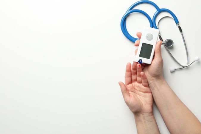 Female checking blood sugar level on blank background