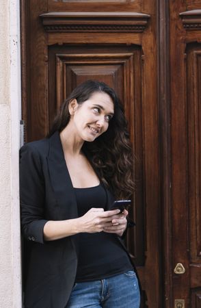 Young female using mobile phone on wooden door